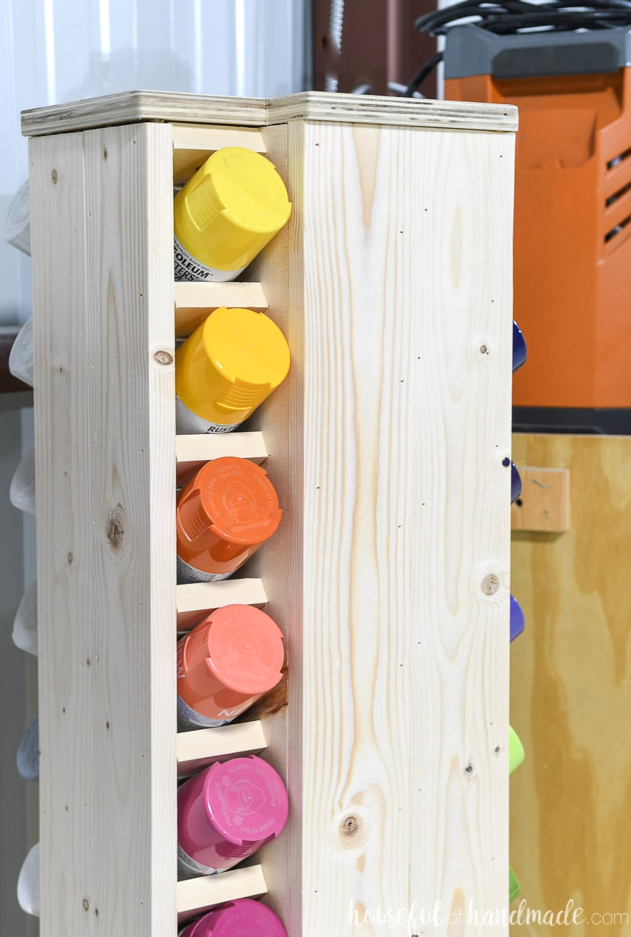 Close-up of the storage cabinet top with yellow, orange, and red spray paint positioned in the slots. 