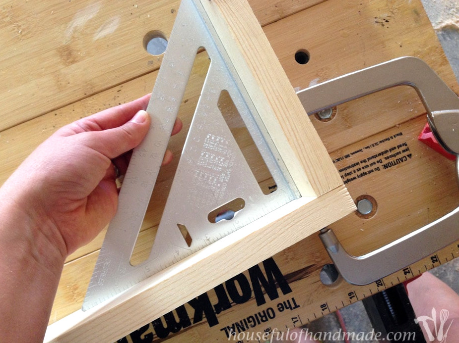 Holding a square up to the corner of the drawer box during assembly.