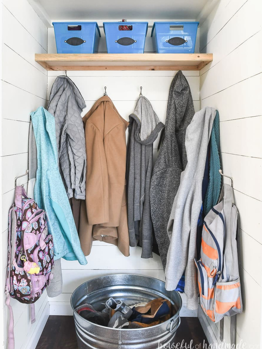Coat closet converted into a farmhouse-style entryway with shiplap walls and coat hooks. 
