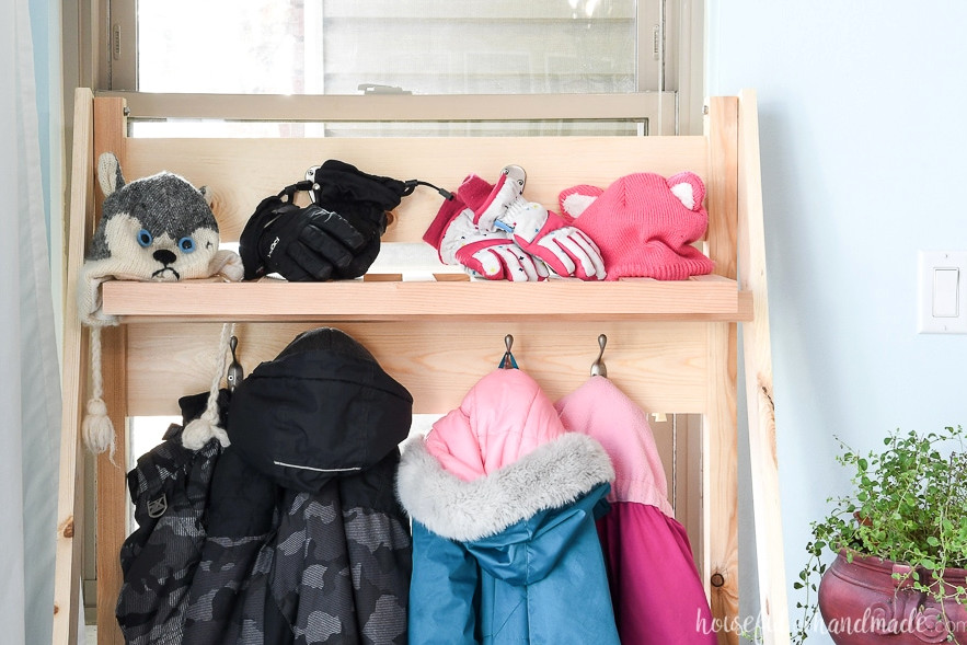 The upper shelf of the collapsible storage rack holding hats and gloves. 