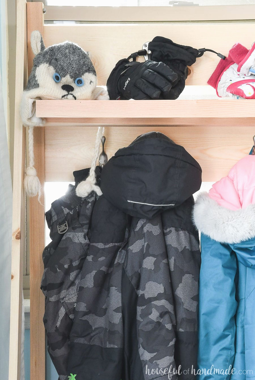 Close-up view of coats hanging on the collapsible storage shelves in the mudroom. 