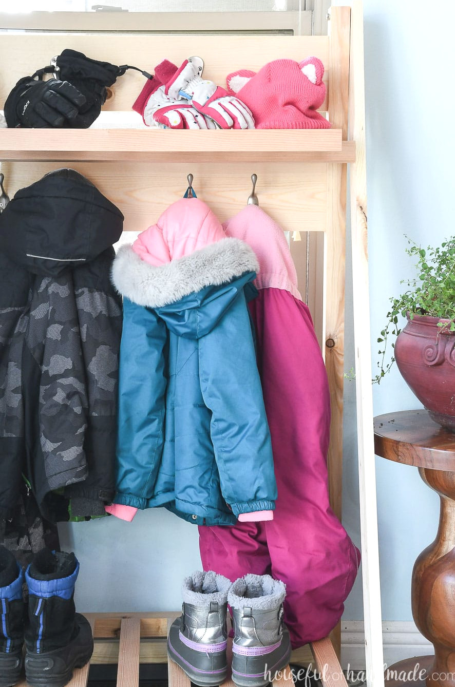 View of the foldable mudroom shelves with coats and winter clothing hanging from them. 