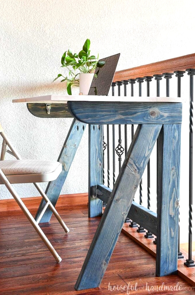 Blue and white homemade folding desk with a laptop and plant placed on its surface.