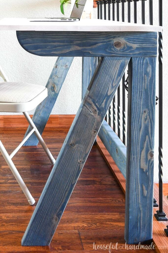 Detailed view of the fold-away desk foundation built from 2x4s and finished in navy blue.