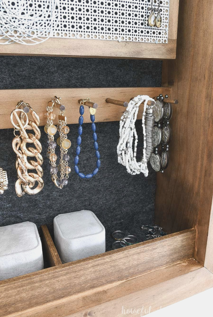 Detailed view of bracelet hooks and ring sections inside the DIY wall jewelry organizer. 