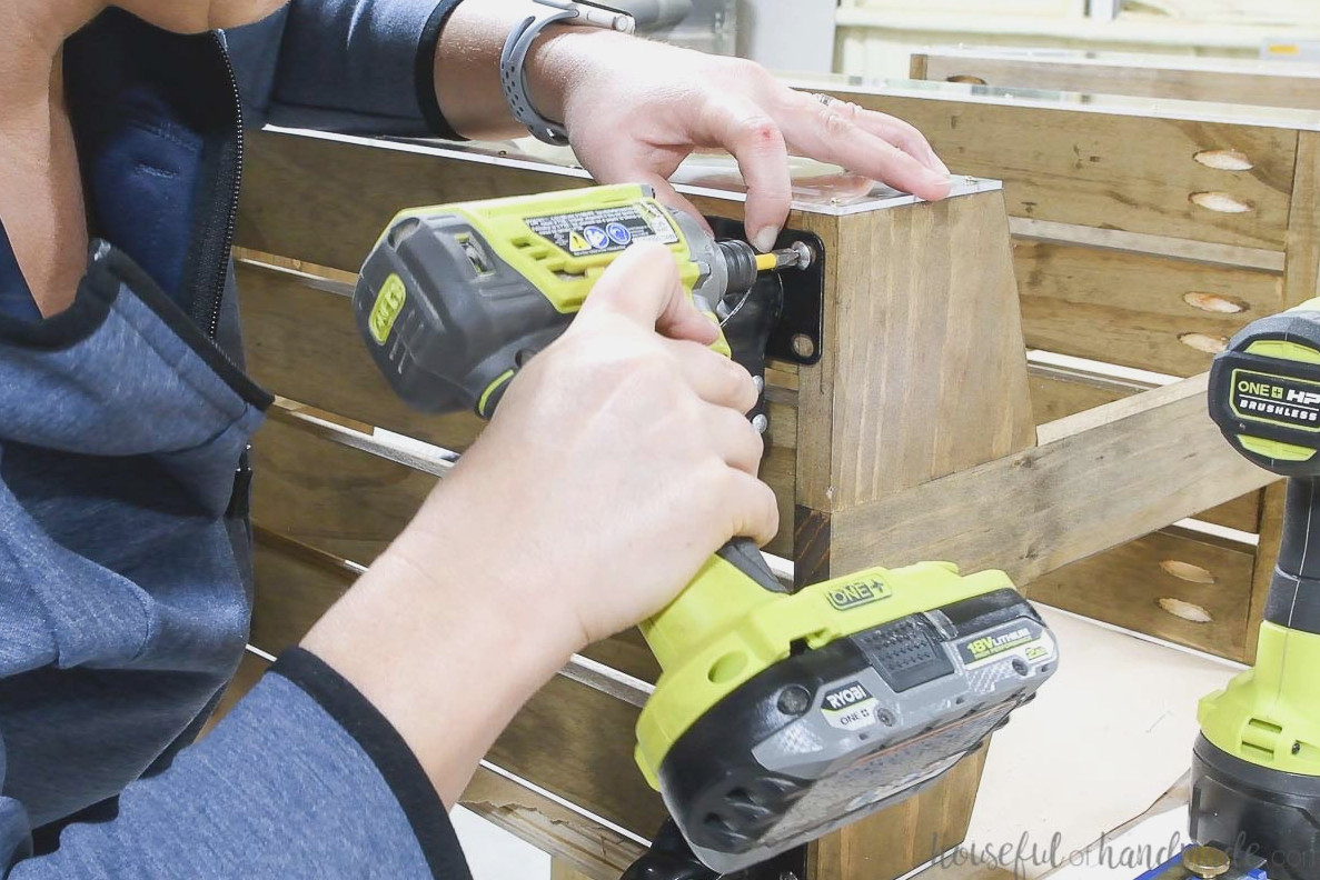 Installing caster wheels on the bottom of the DIY wooden rolling cart.