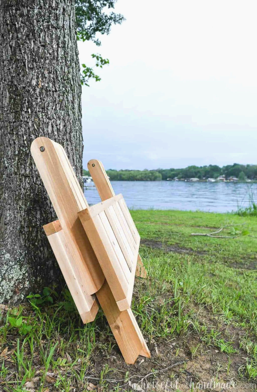 Folding outdoor picnic table collapsed and resting against a tree. 