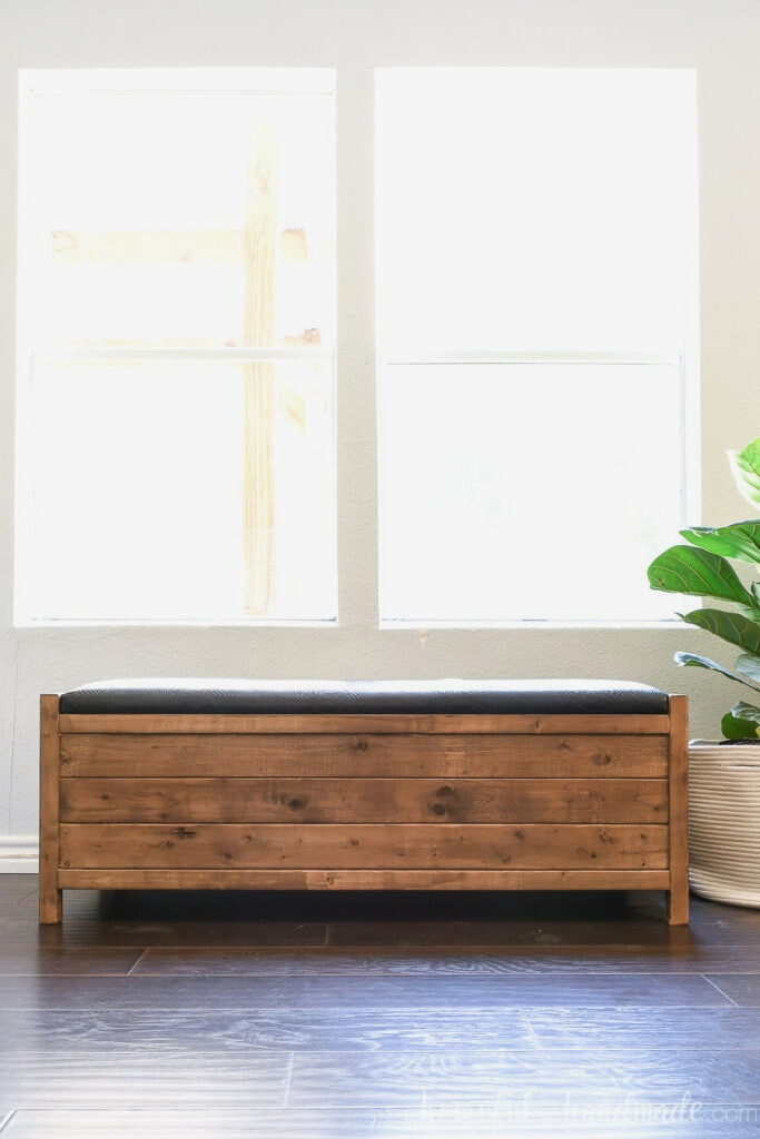 View from the front of the uncomplicated wooden storage bench with a lift-up black leather top.