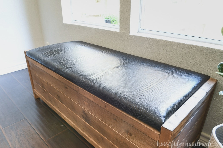 Close-up image of the black leather-covered cushion on the wooden bench.