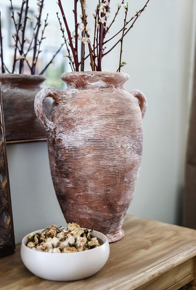 large handled jug vase on table with branches