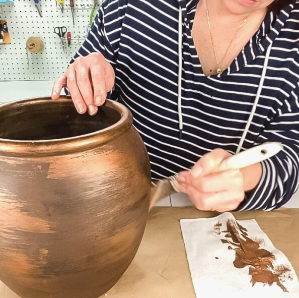 applying copper-colored paint to the planter