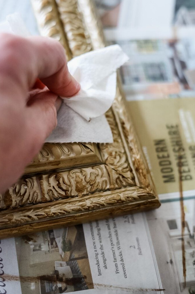 wiping off excess antique wax from gold picture framea