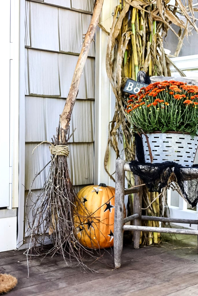 autumn porch arrangement featuring a witch broom and pumpkin.