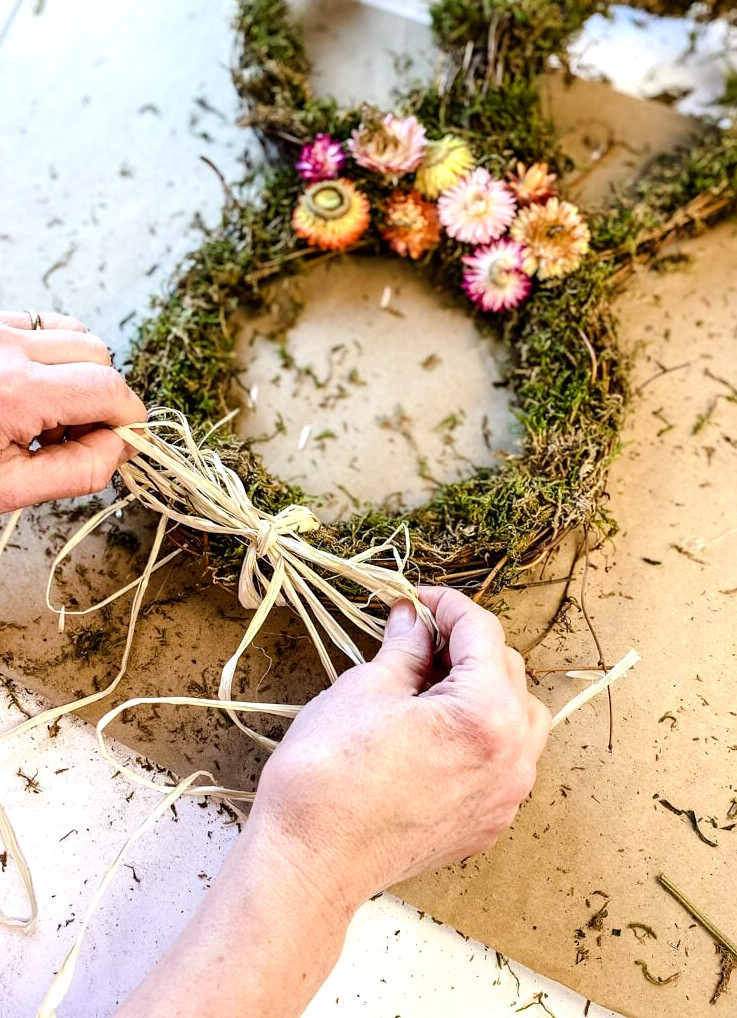 attaching a raffia bow to a wreath