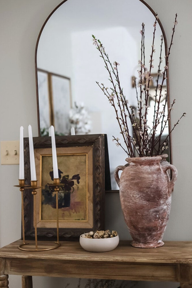 entryway table with large vase, cherry blossom branches, and painting