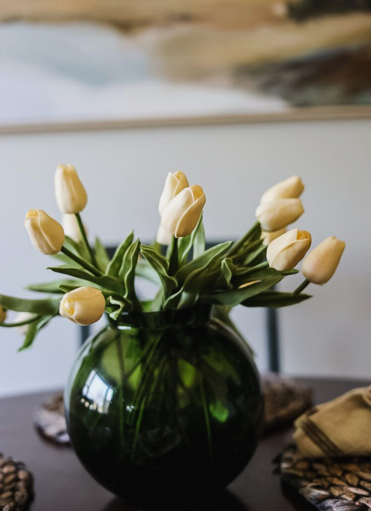 white artificial tulips in green glass vase