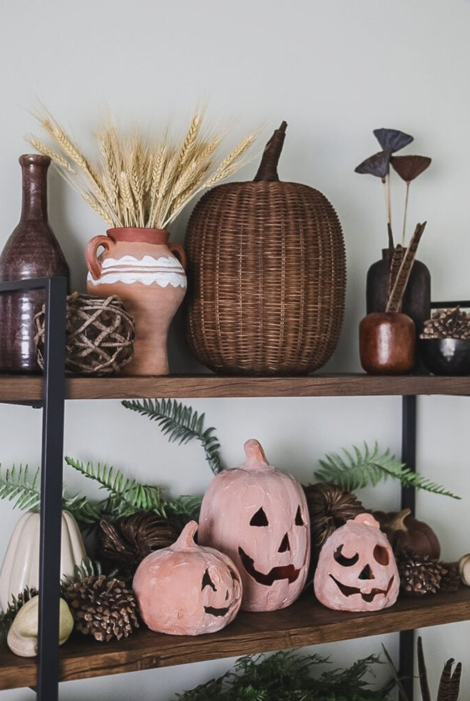 book shelf with fall decor including pumpkins and dried flowers