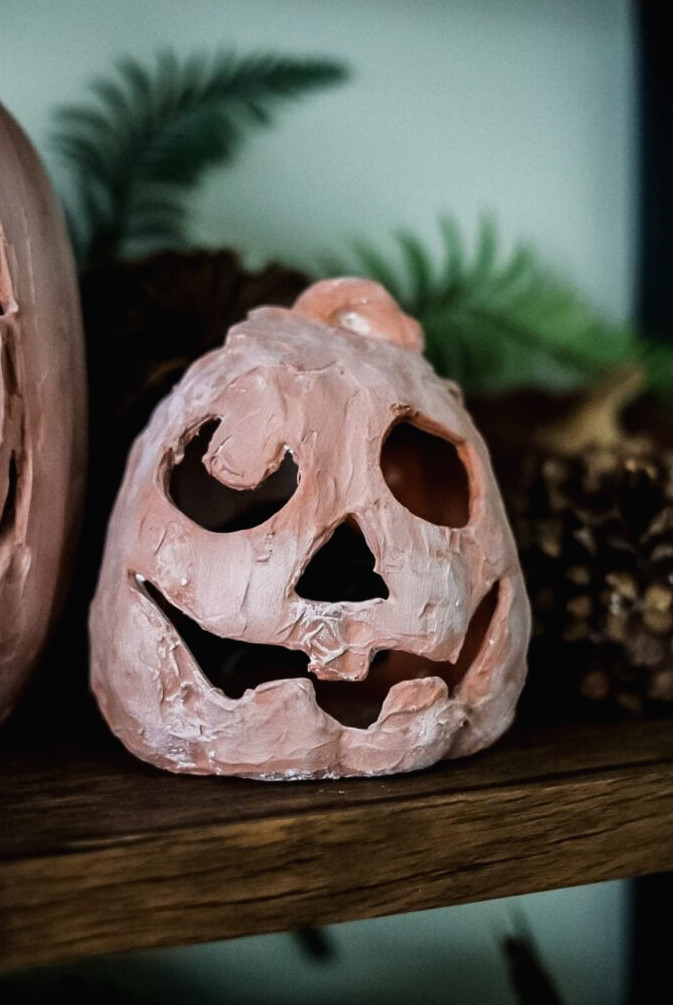 small terracotta looking pumpkin on a bookshelf