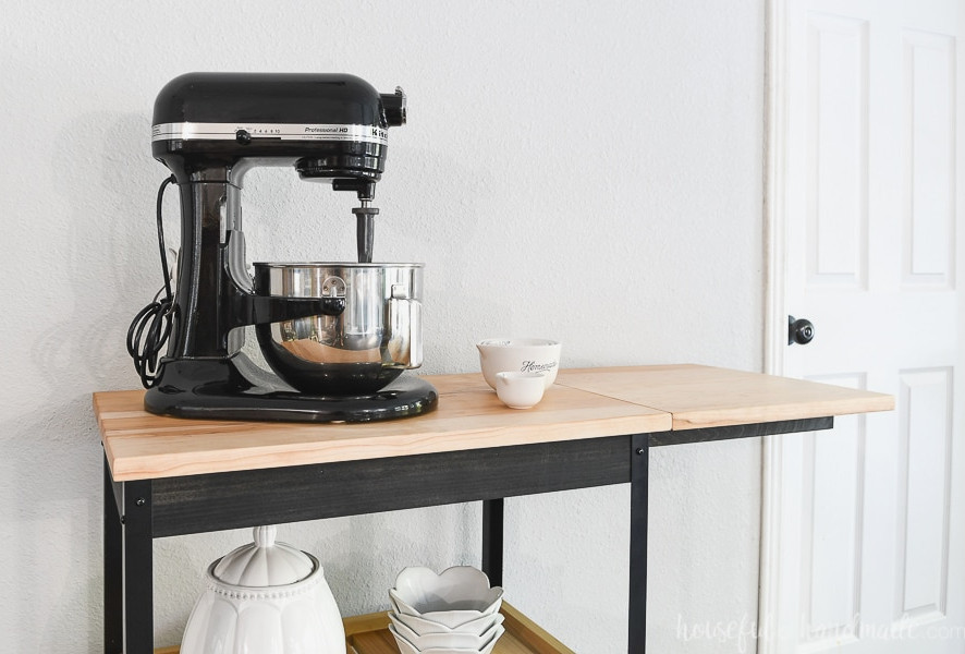 Close-up view of the kitchen cart top with the drop-down leaf raised beside a KitchenAid mixer. 