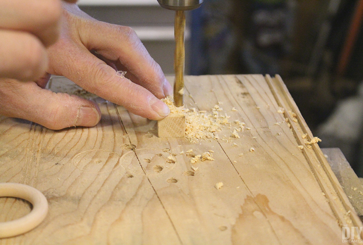 Drilling a hole in the bottom of a small wooden piece to fit the ring.