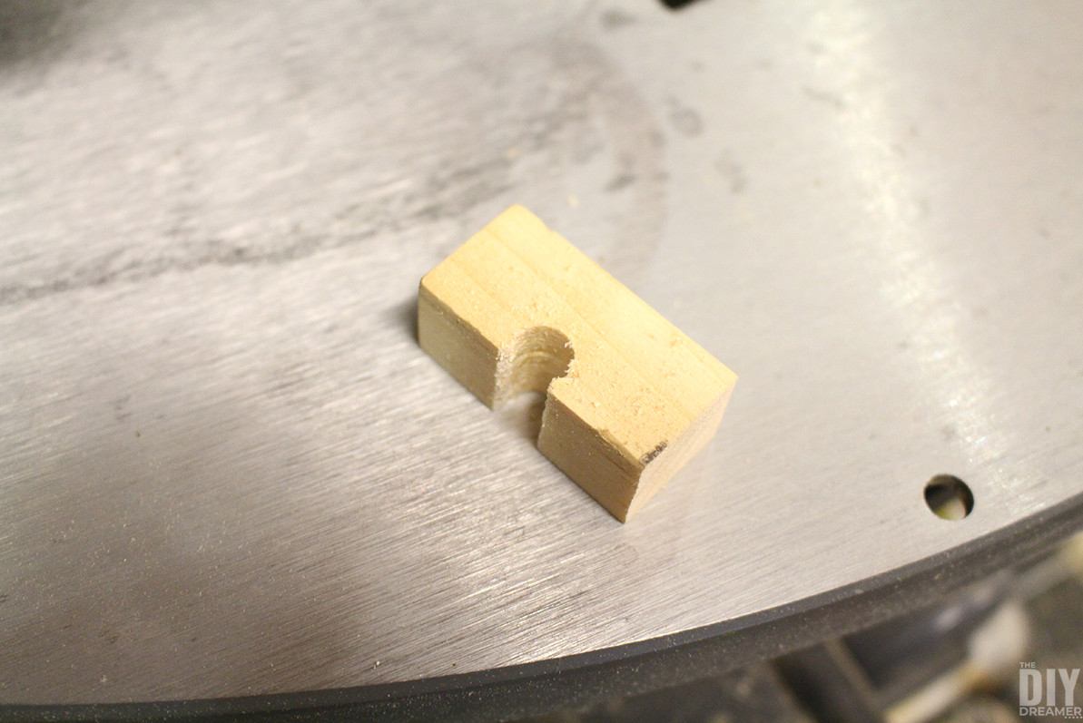 Wooden piece for holding the ring, resembling a small bridge.