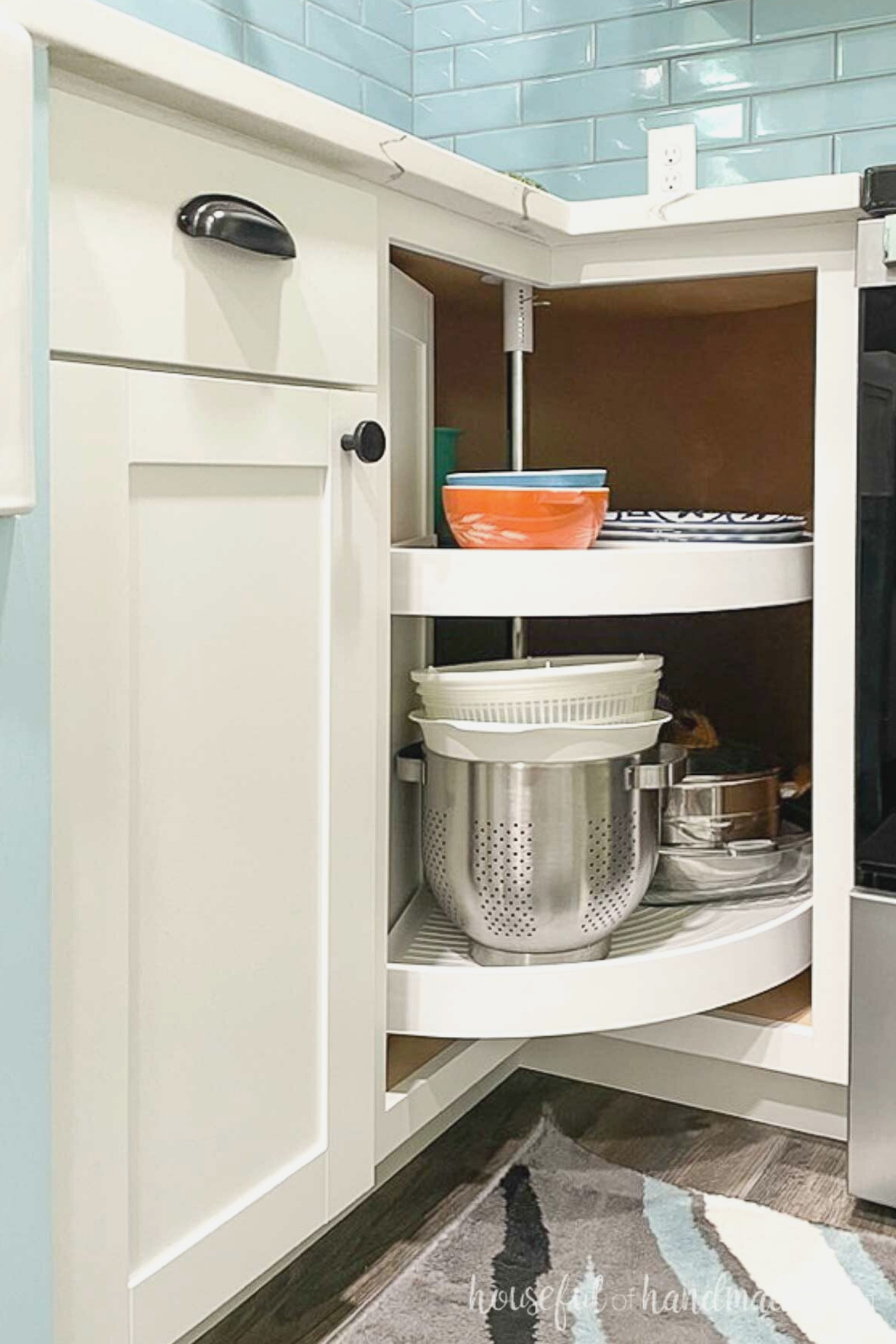 Bifold corner cabinet open showing a lazy Susan turntable inside it with dishes.