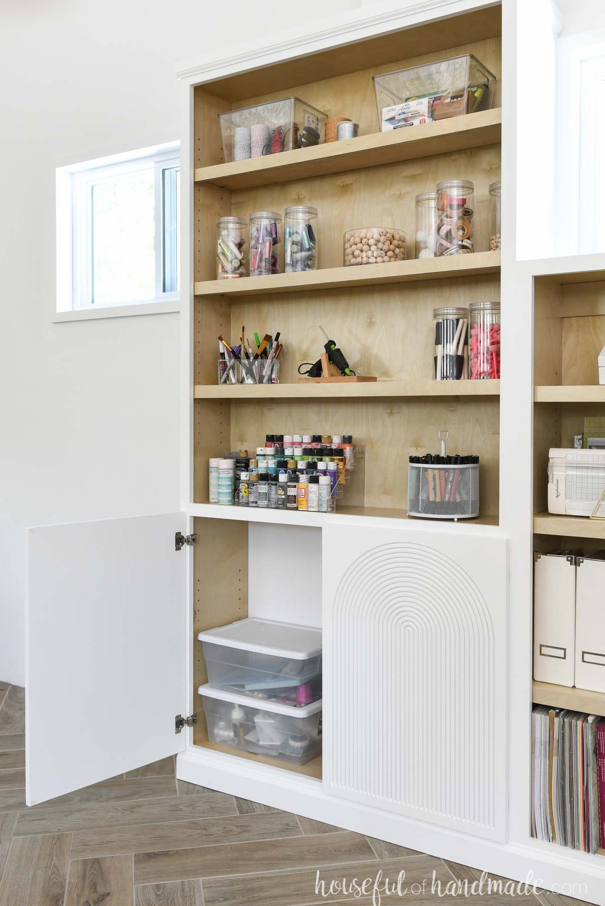 Built in bookcases with doors on the lower section and one door open showing the inside. 