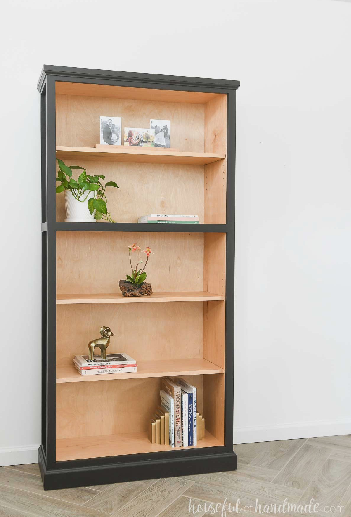 DIY tall bookcase with 5 shelves with natural wood on the inside and black paint on the outside.
