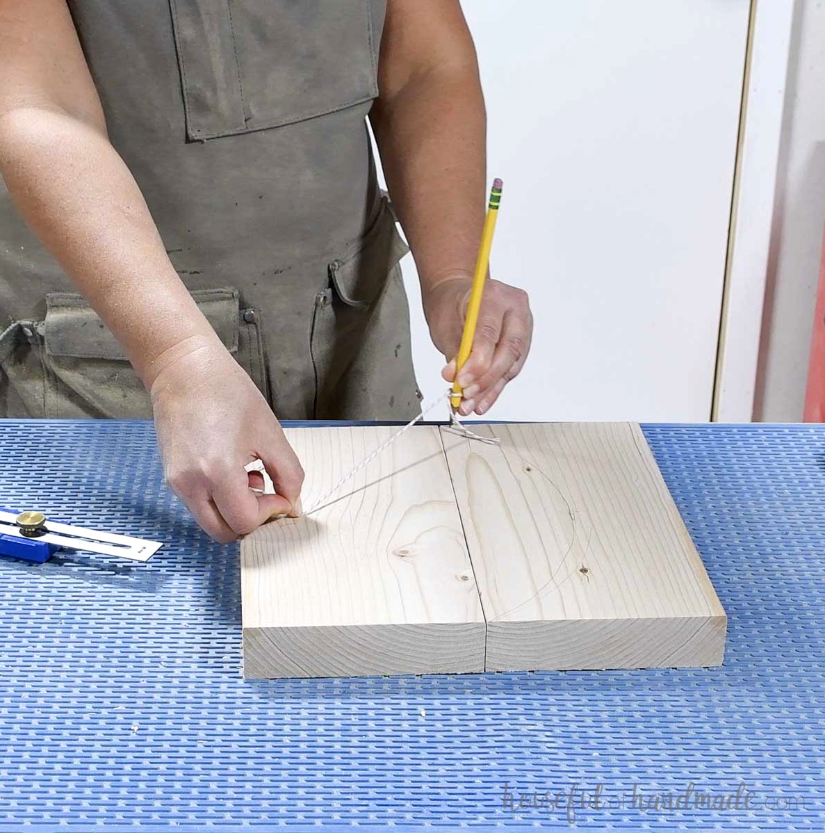 Drawing an arch on a board with a pencil and string.