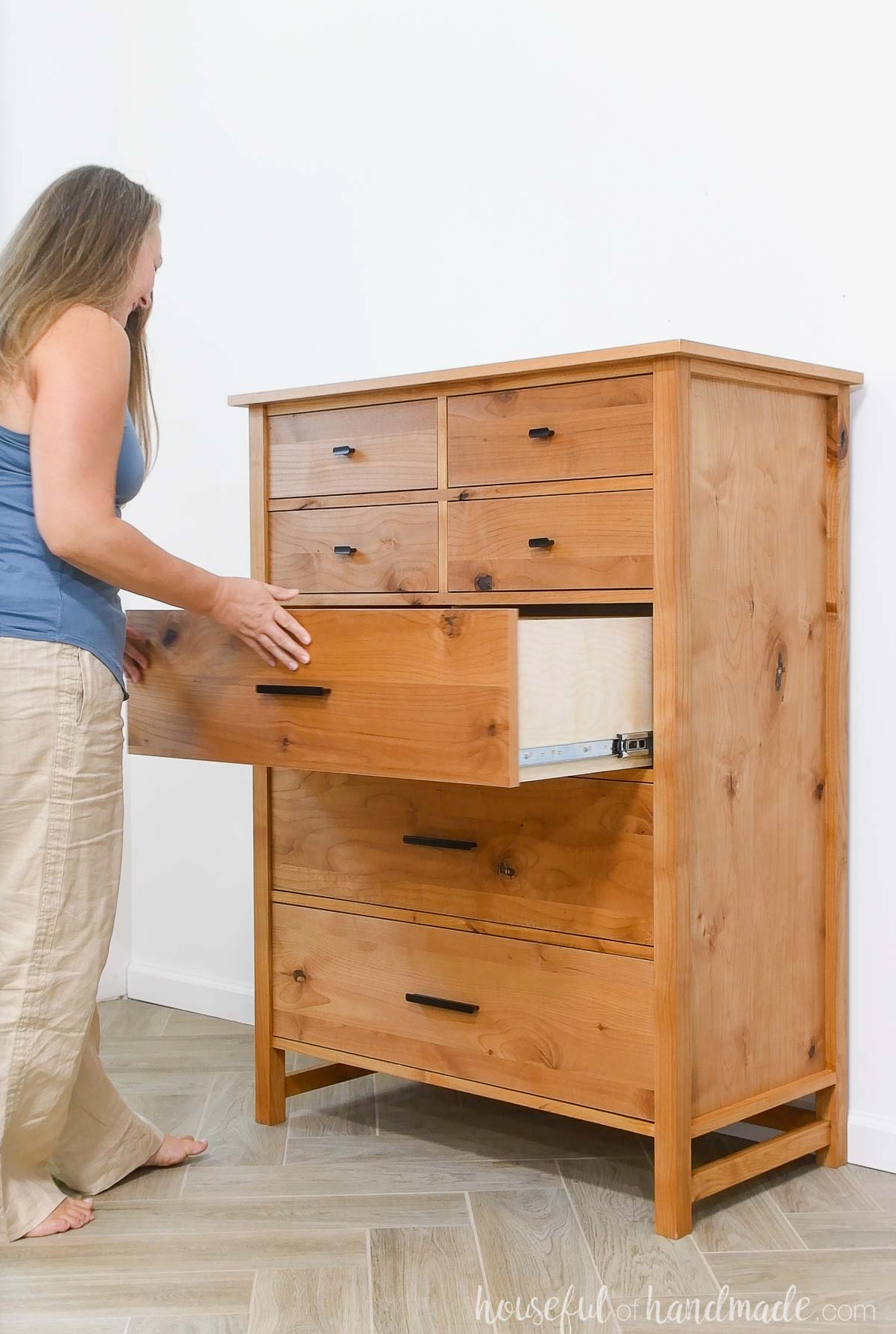 Woman opening a drawer in the tall dresser with 7 drawers. 