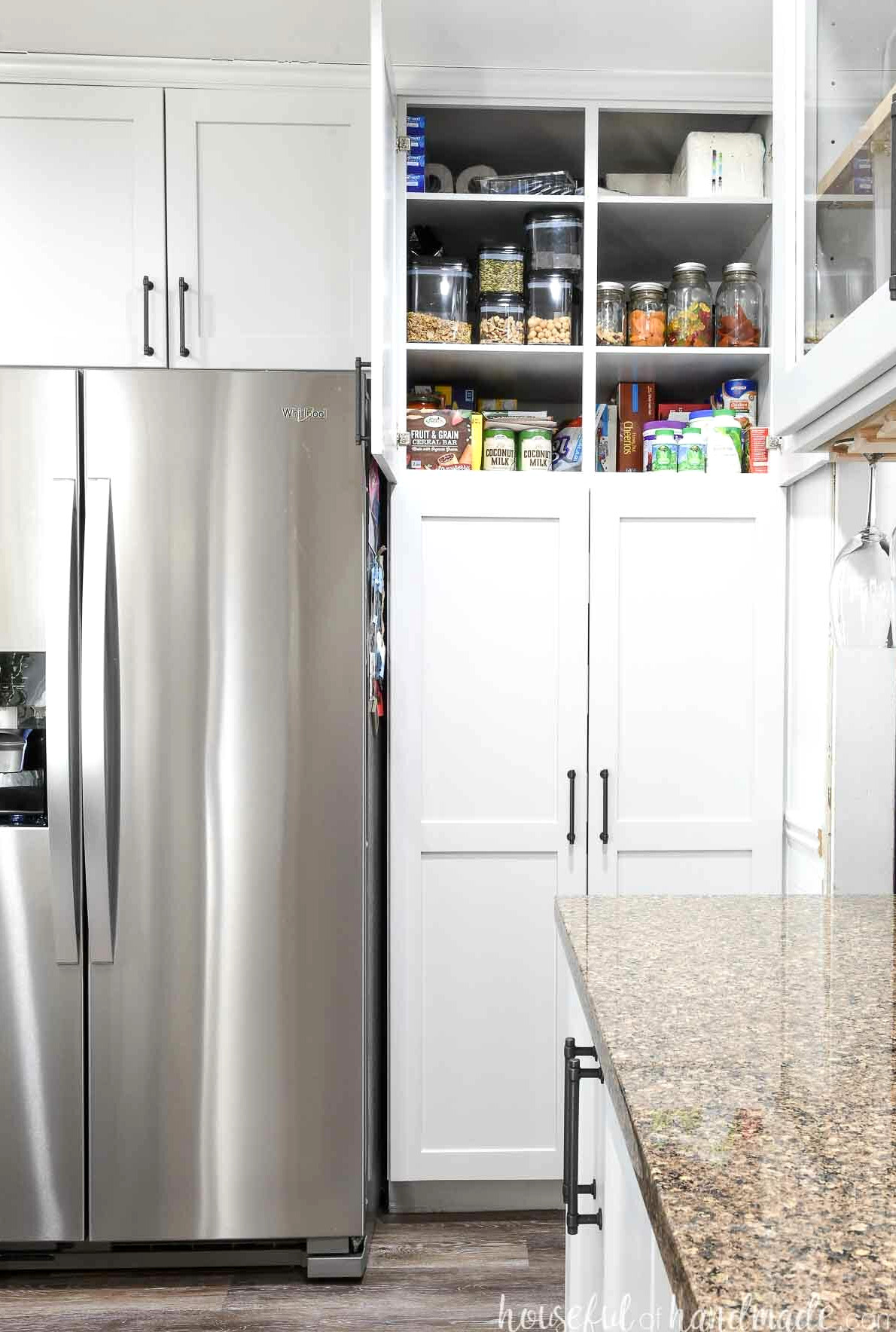 Pantry cabinets positioned around a refrigerator, with the upper doors open to reveal the interior shelves.