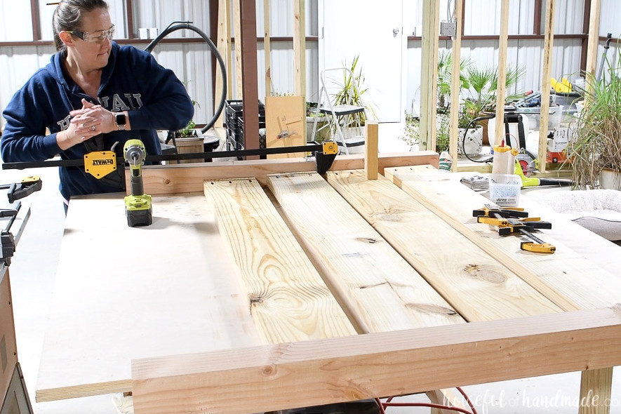 Using a clamp to correctly align the 2x8 boards before fastening them to the leg.