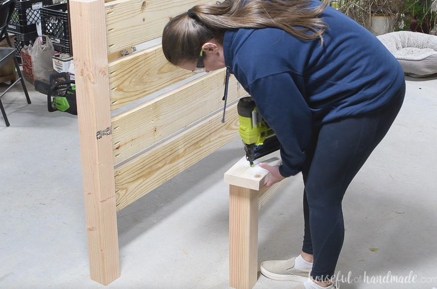 Using a nail gun to fasten the board across the footboard top.