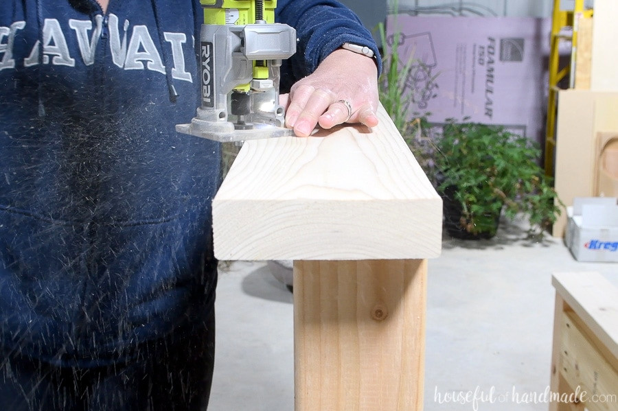 Using a palm router to round over the top edges of the headboard.
