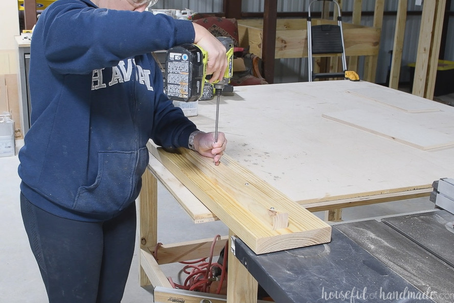 Fastening the 2x2 board to the bed rails using 2 1/2" screws.