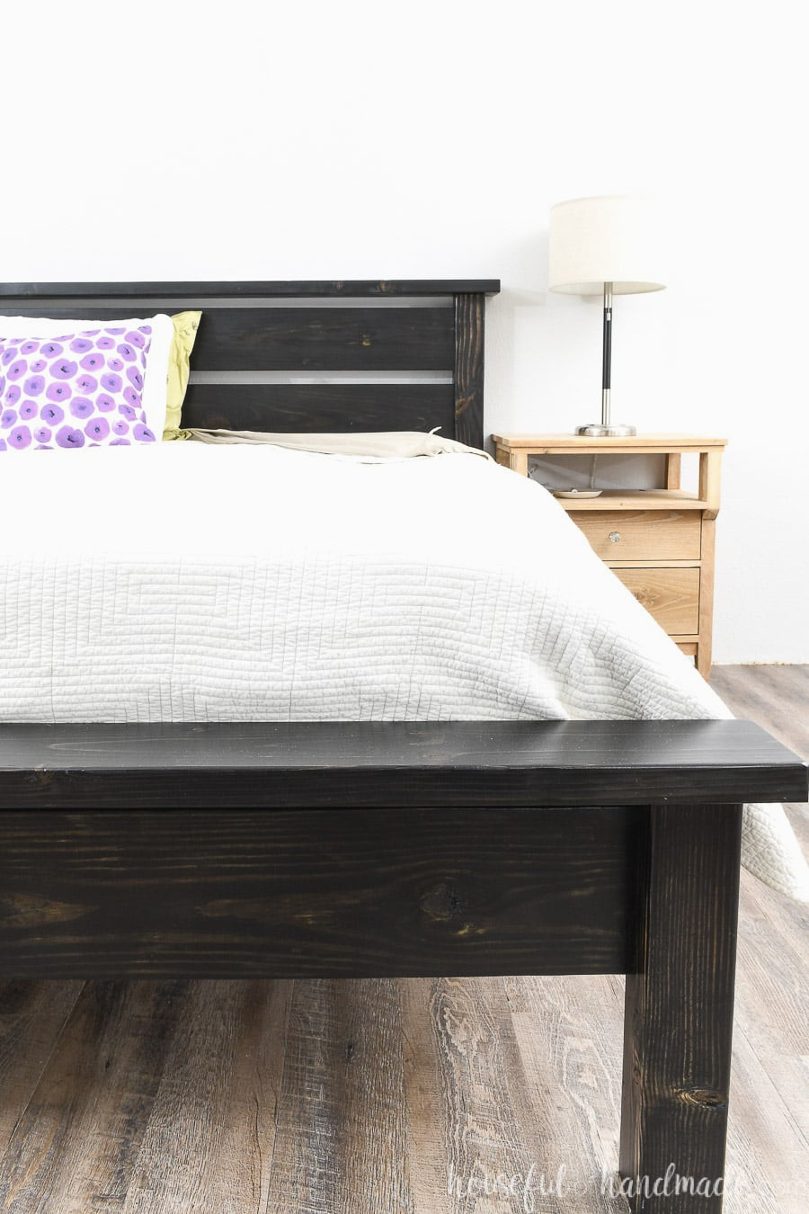 DIY platform bed with a traditional appearance and a slatted headboard beside a nightstand.