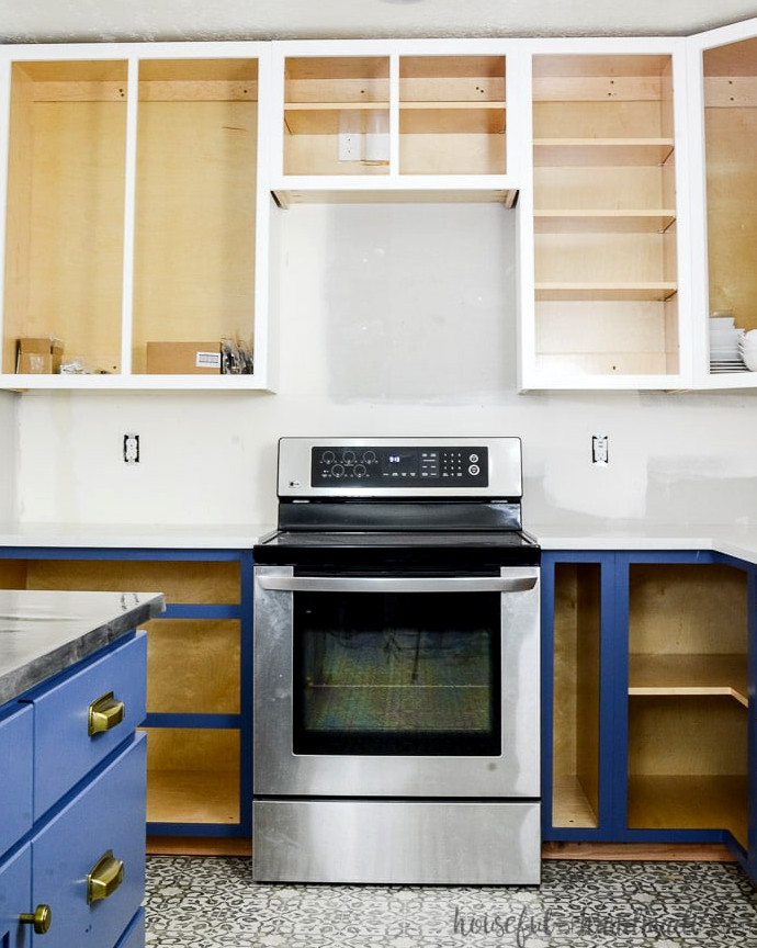 White upper cabinets with soft navy lower cabinets without doors. Learn how to paint unfinished cabinets at Housefulofhandmade.com.
