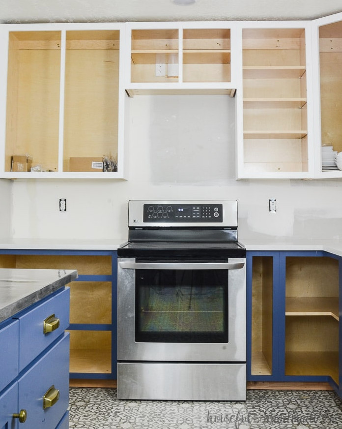 White-painted upper cabinets paired with soft navy base cabinets without doors. Learn how to paint unfinished cabinets at Housefulofhandmade.com.
