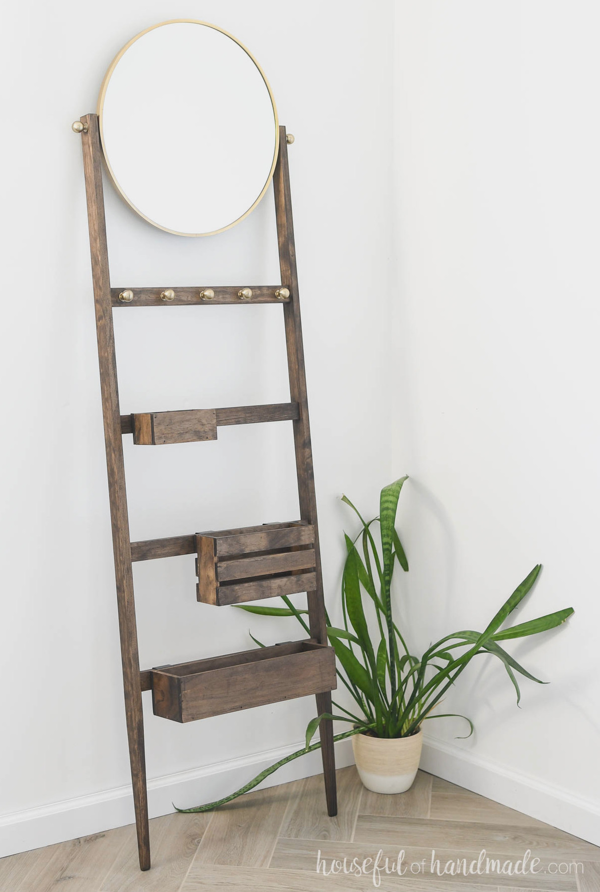Storage ladder with bins and a mirror on top, leaning against the wall.