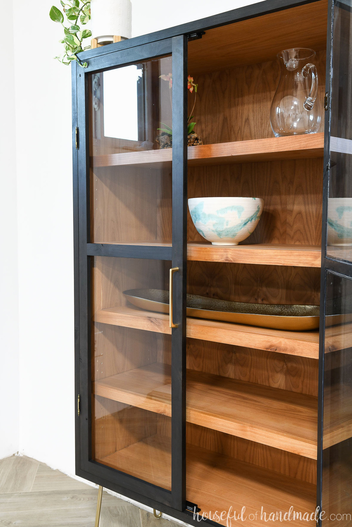 Close-up view of the black-and-wood curio cabinet with one door opened.