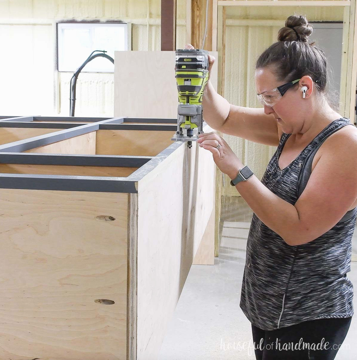 Using a trim router to flush-cut the face frame side with the cabinet box.