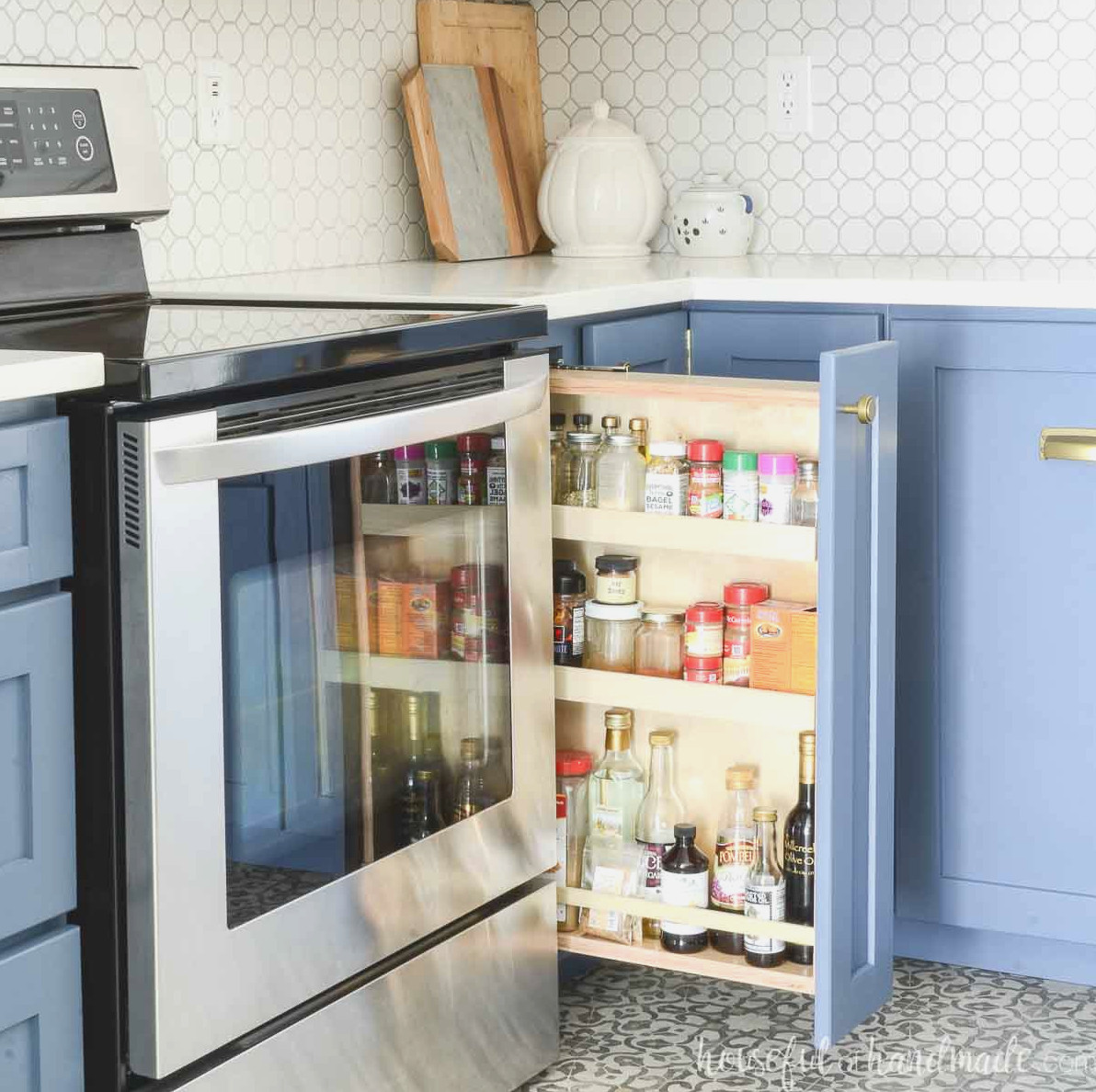 DIY pull out spice rack cabinet with 3 shelves in a kitchen with blue cabinets.
