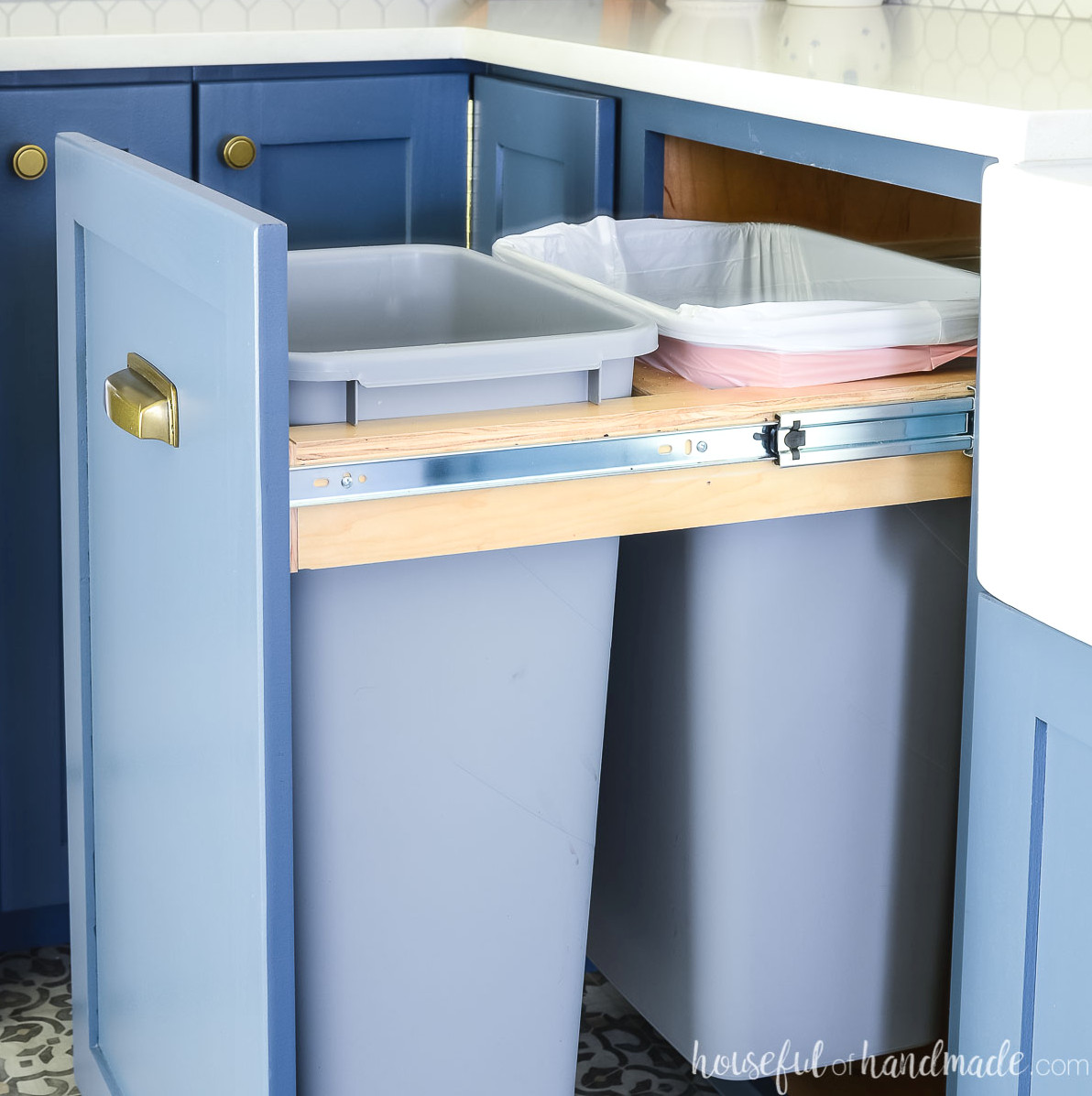Pull out trash can cabinet slid open revealing the two large garbage cans inside.
