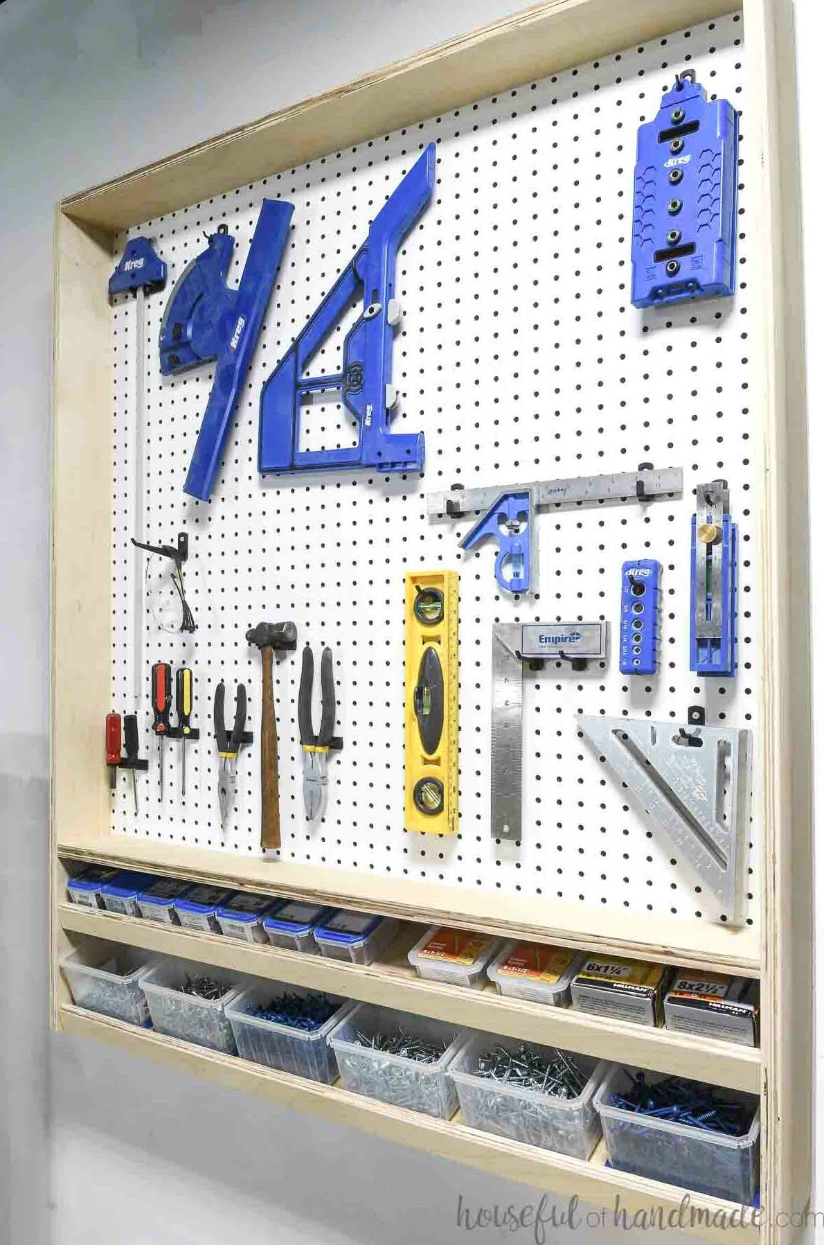 Pegboard wall organizer framed with plywood and featuring angled lower shelves for storing screws. 