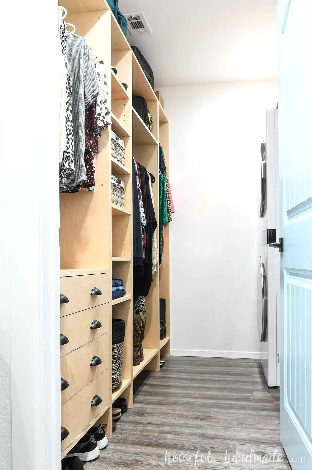 Narrow closet with wood closet system on one side and a stackable washer/dryer on the other.