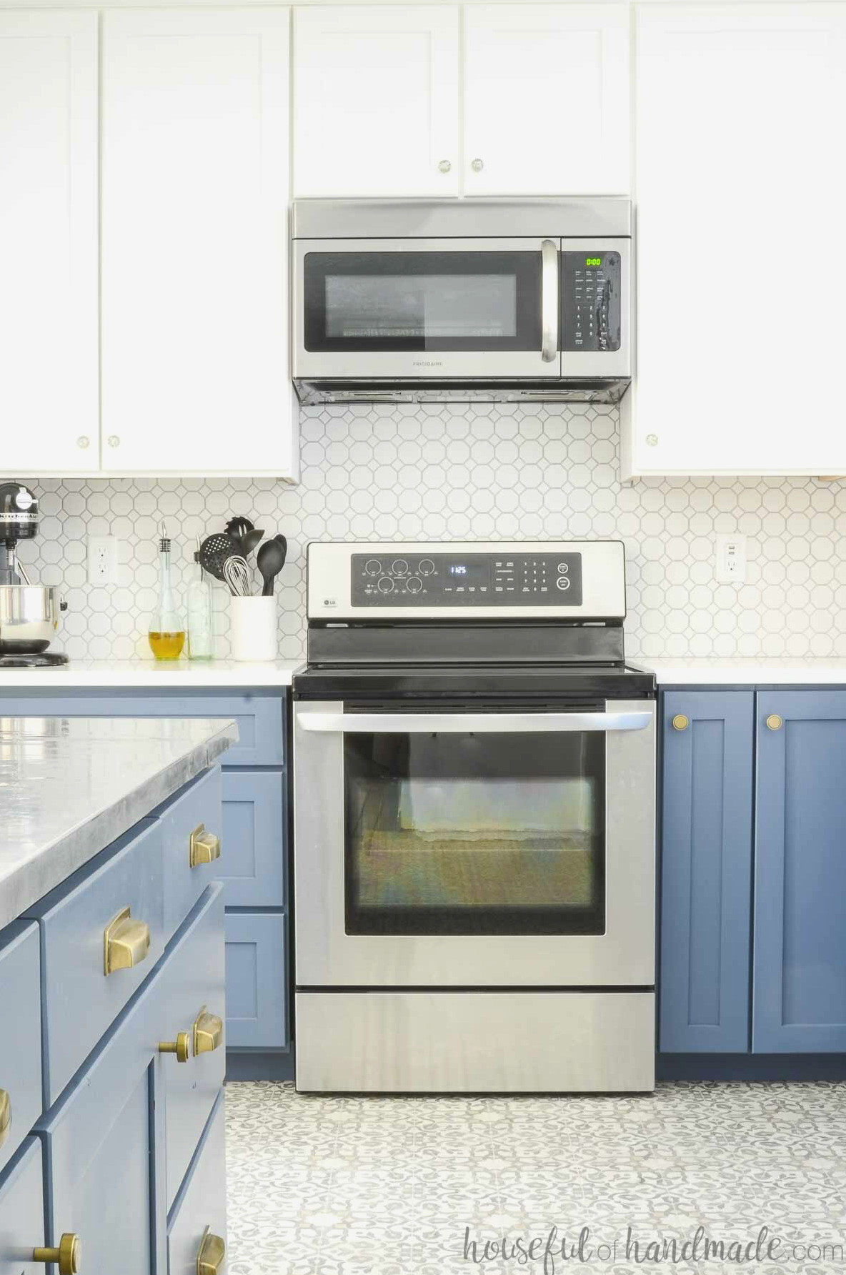 Kitchen featuring white upper cabinets, blue lower cabinets, and a slim spice cabinet beside the stove. 