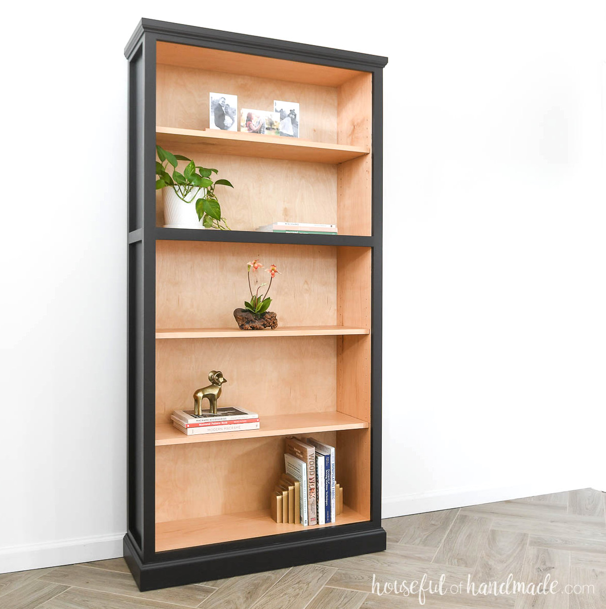 DIY tall plywood bookcase with a wood-finished interior and black-painted exterior.