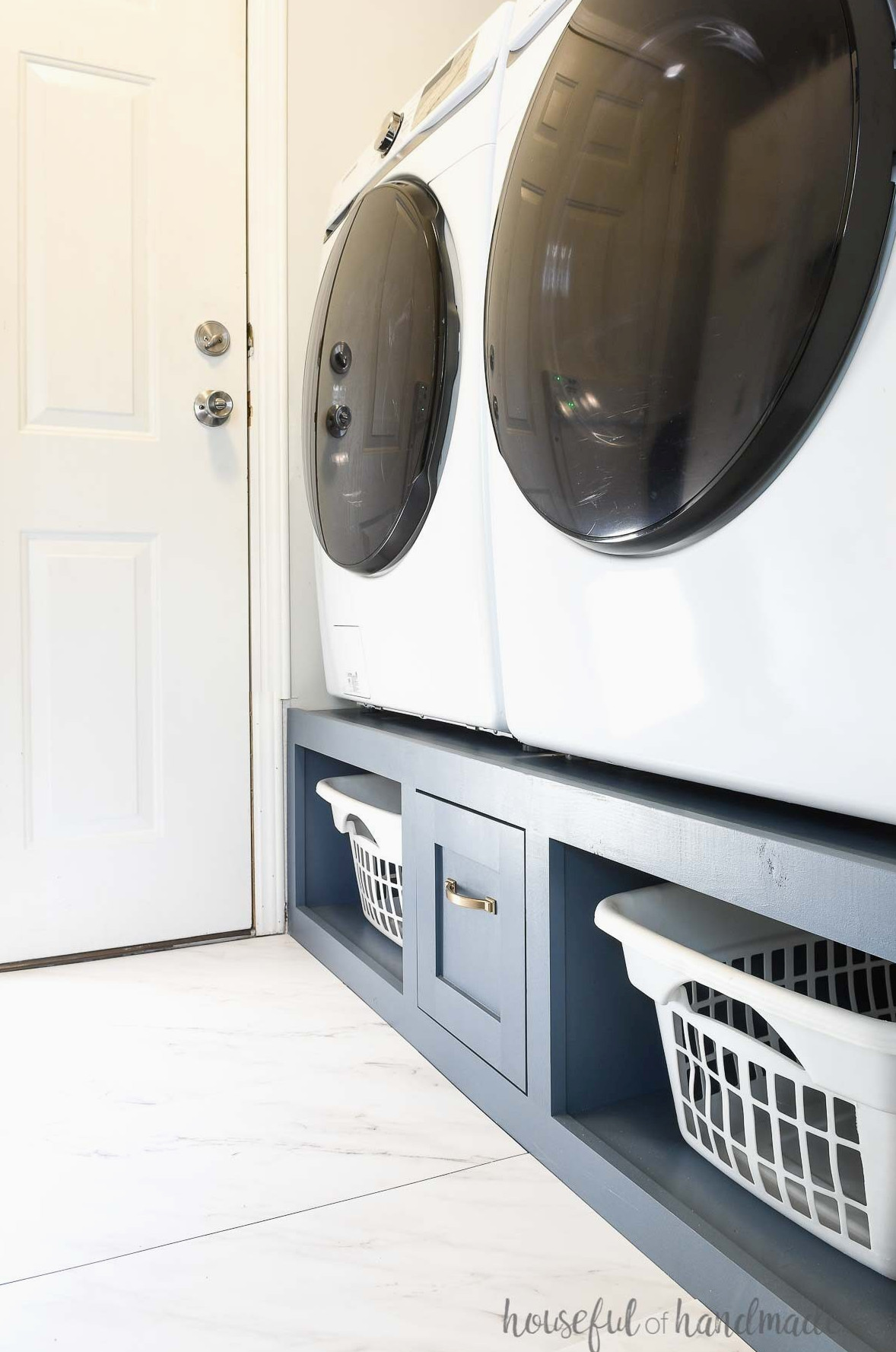 White washer and dryer on a blue painted DIY platform with storage. 