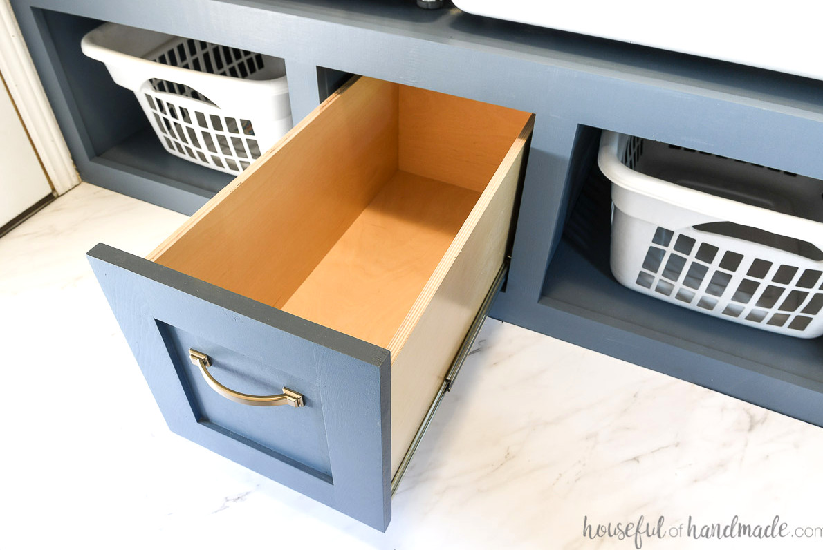 Large drawer in the center of the washer and dryer platform opened up looking inside it. 