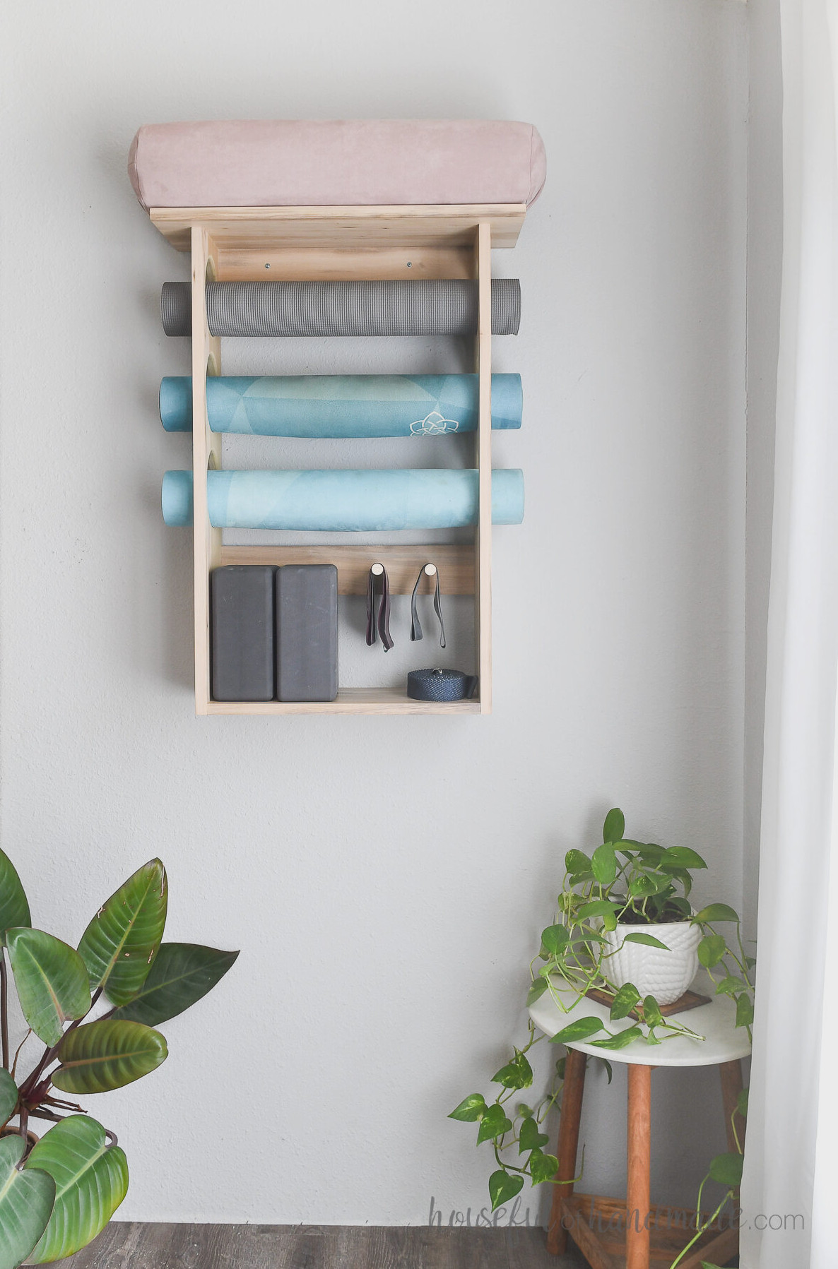 DIY exercise mat organizer with shelves for storing extra workout equipment, attached to a wall. 